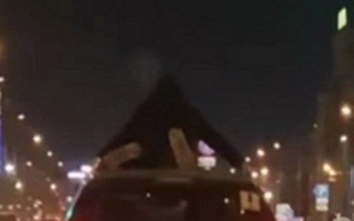 Человек едет на крыше автомобиля
